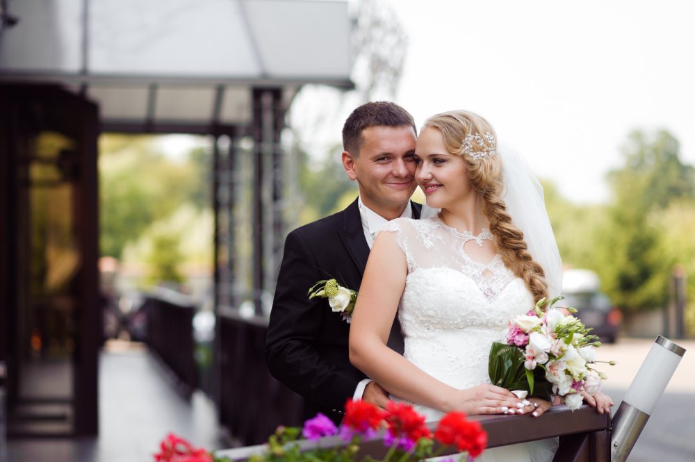 Leo and Maya together on a balcony with her bouquet